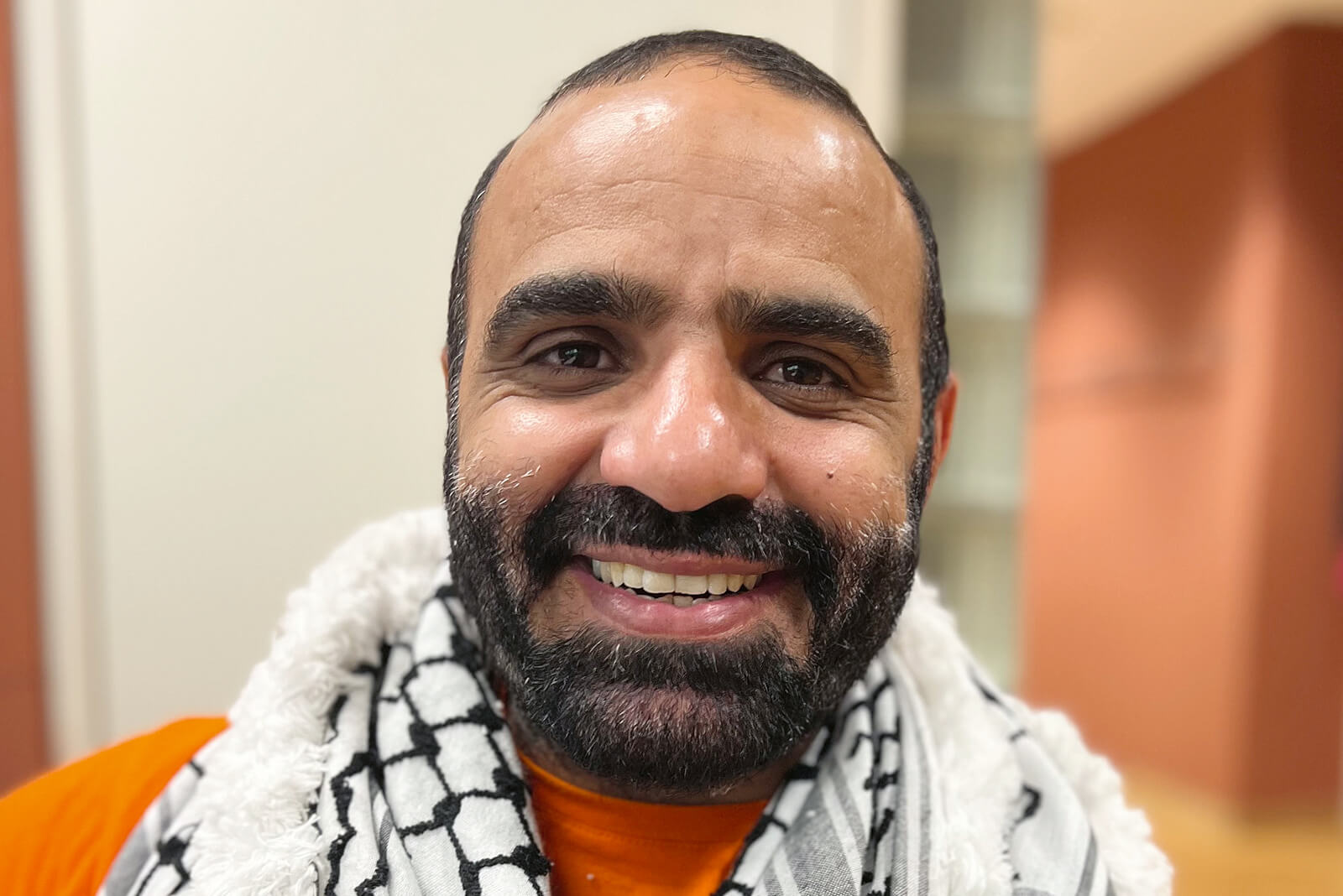 Porträt von Mansoor Adayfi: Ein freundlich dreinblickender Mann mit Bart lächelt.