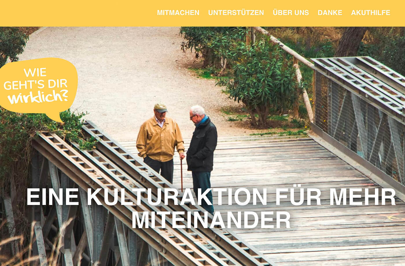 Werbesujet wiegehtsdirwirklich.org: Schrift auf einem Bild zweier älterer Männer im Gespräch auf einer Brücke stehend.