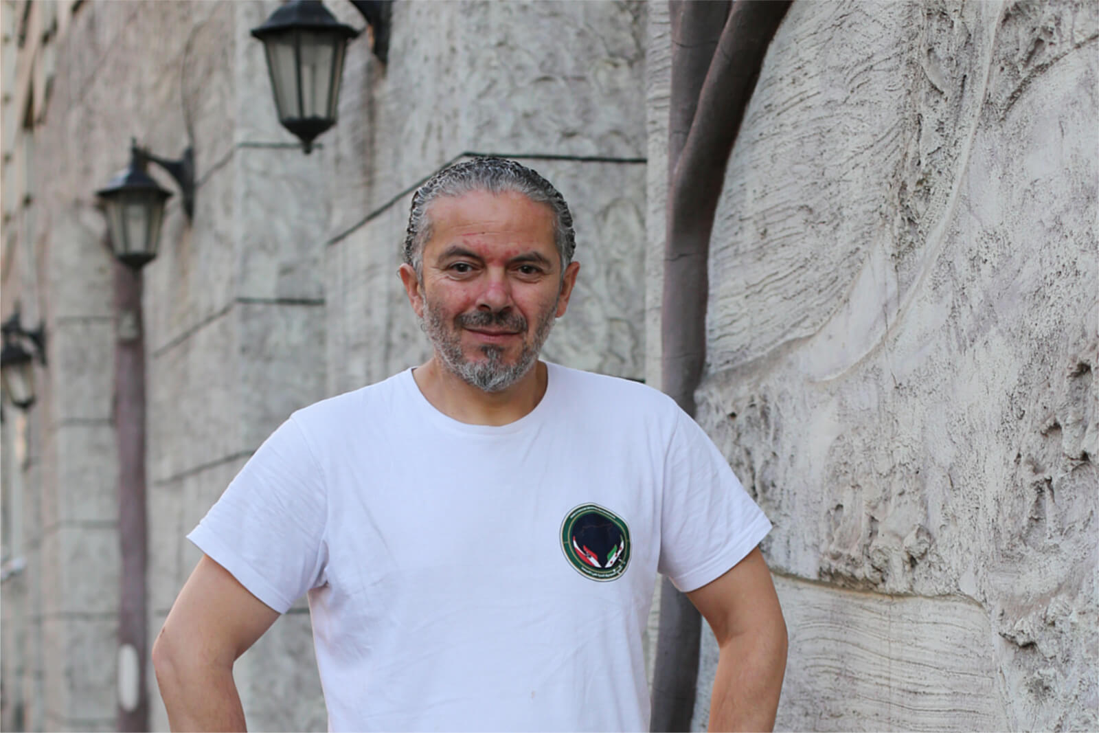 Porträt von Abdulhkeem Alshater: Ein Mann im weißen T-Shirt blickt freundlich und entspannt.