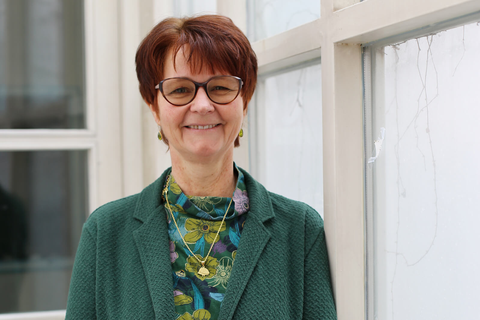 Porträt von Gertrude Jaksch-Fliegenschnee: Eine Frau mit Brille und kurzen Haaren lächelt freundlich.