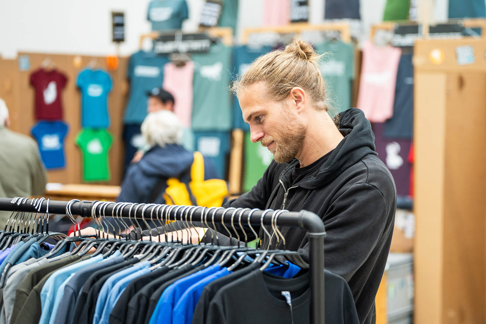 Ein Mann schaut an einem Kleiderständer T-Shirts durch.
