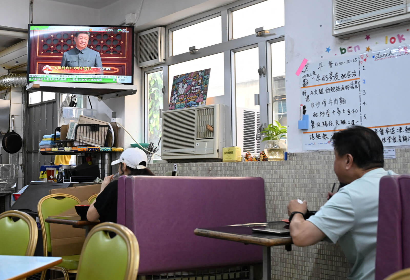 Ein chinesischer Mann isst im Restaurant und schaut währenddessen eine Ansprache des Staatspräsidenten Xi Jinping.