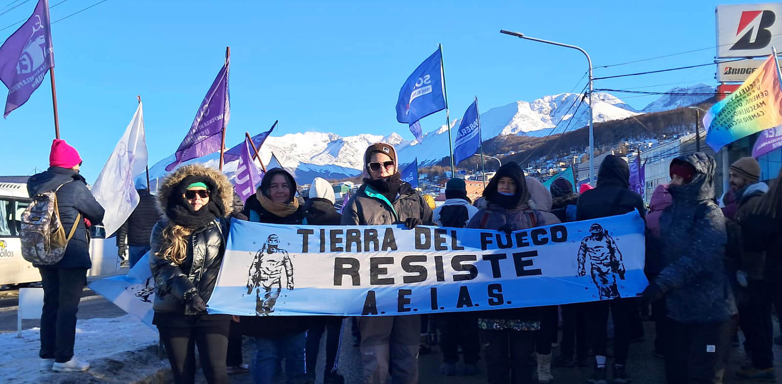 Menschen protestieren im Schnee und halten ein Banner mit „Tierra del Fuego Resiste“.