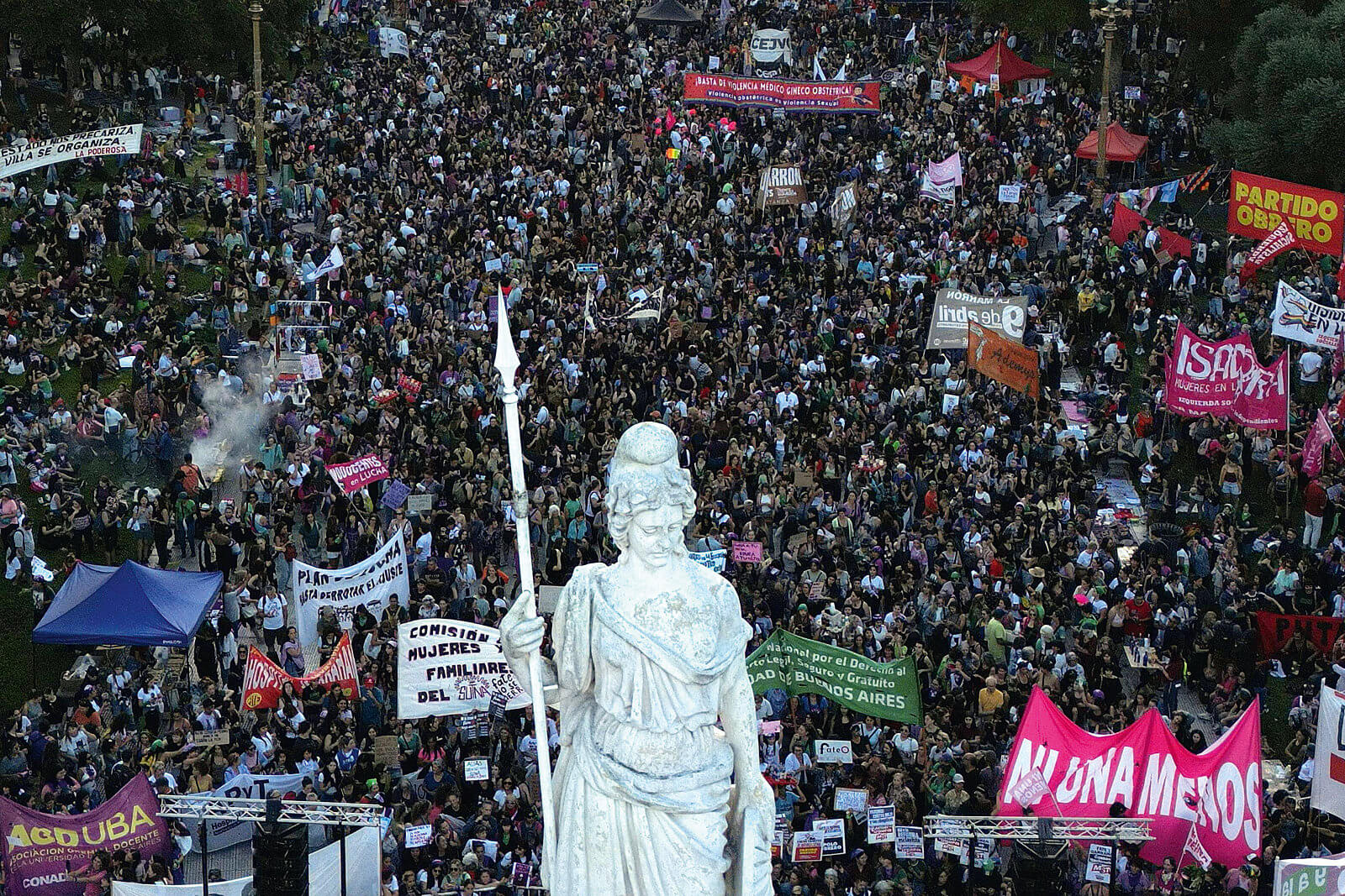 Luftaufnahme einer Massenkundgebung in Buenos Aires rund um eine Statue – Tausende Demonstrierende mit Bannern der Bewegung „Ni Una Menos